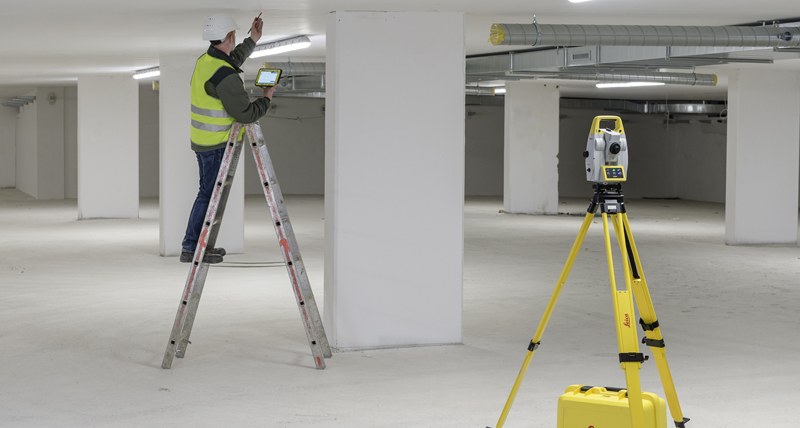 MEP/HVAC specialist on a lader, marks points in the ceiling whilte the Leica iCON iCT30 layout tool automatically turns and highlights the point position with the laser beam